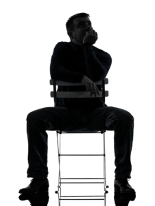 Scherenschnitt eines kaukasischen Mannes der frontal verkehrt herum auf einem Stuhl sitzt