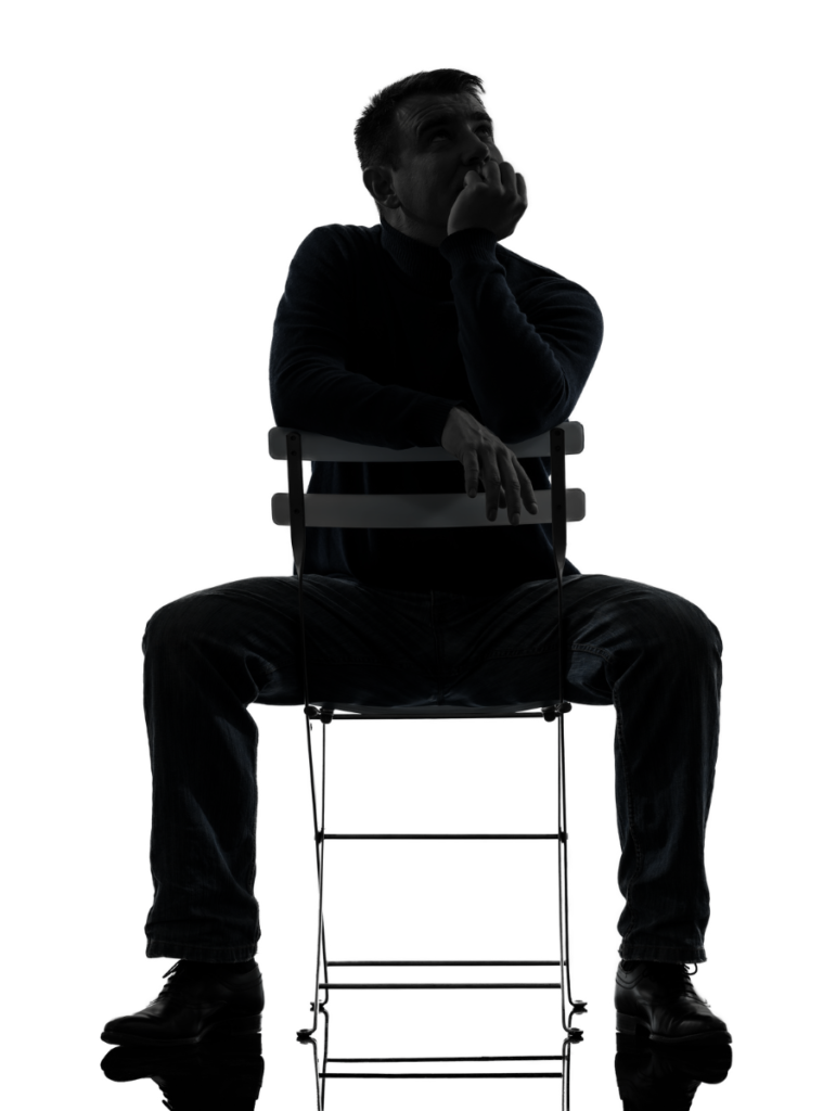 Scherenschnitt eines kaukasischen Mannes der frontal verkehrt herum auf einem Stuhl sitzt